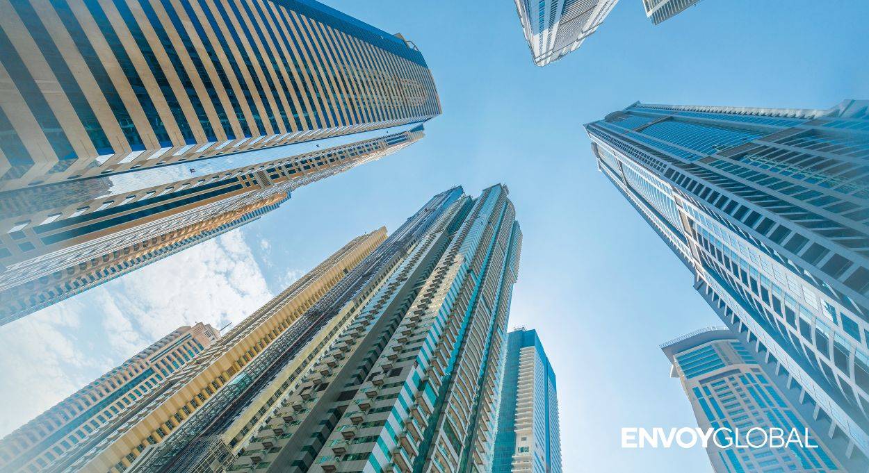 An image looking up on Dubai's cityscape with a white logo reading Envoy Global.