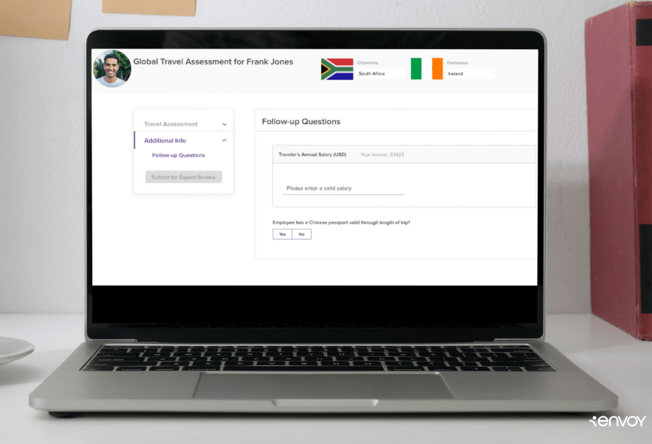 Image of an open laptop on a desk with books and a coffee cup. The screen shows a screenshot of Envoy's Global Assessment Tool.