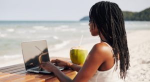 Image of women working remotely on a laptop at the beach.